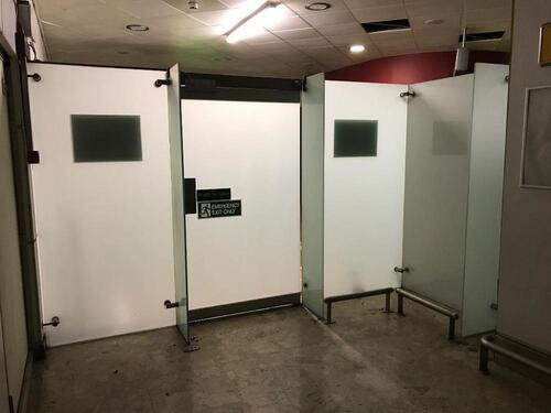 Glass paneled security area with metal entrance and electric door.