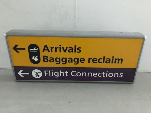 Arrivals Baggage Reclaim Flight Connections'  Illuminated sign, curved metal construction.
