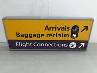 Arrivals Baggage Reclaim Flight Connections'  Illuminated sign, curved metal construction.