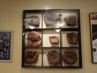 THROWBACK BASEBALL MITTS FRAMED IN A WOODEN / GLASS DISPLAY - HOLDS (9) MITTS (38" X 38") - (LOCATION: 1ST FLOOR STRIP SIDE BAR)