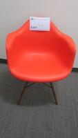 HERMAN MILLER "EAMES" MOLDED PLASTIC ARMCHAIR, WALNUT FINISH WOOD DOWEL BASE, RED ORANGE SEAT AND BACK. MSRP $666