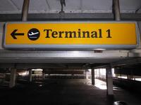 Terminal 1 direction sign, illuminated. Curved metal edge construction including internal light fittings.