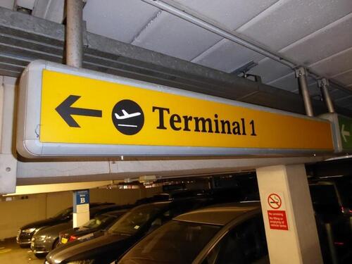 Terminal 1 direction sign,(long) illuminated. Curved metal edge construction including internal light fittings.
